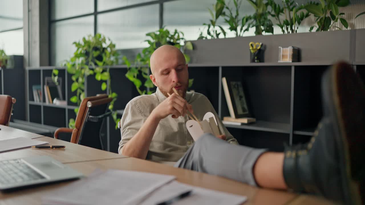 Man Eating Lunch in Office with Legs Up