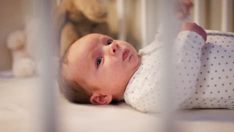 Newborn-Baby-Boy-Lying-On-Back-In-Nursery-Cot-At-Bedtime