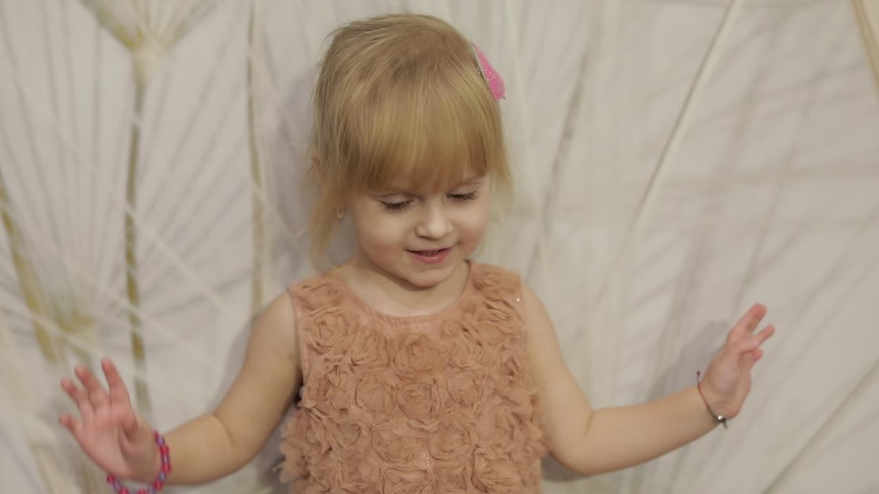 feliz niña de tres años hacer caras y bailar. niño rubio lindo