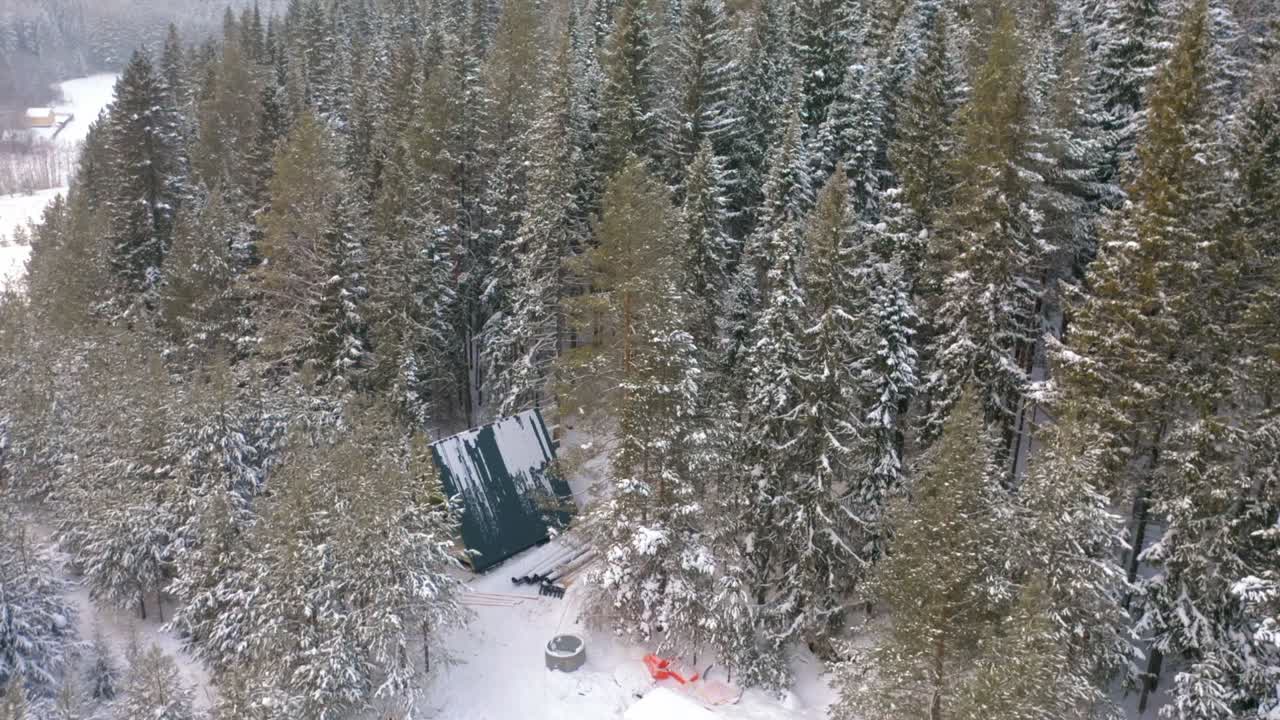 Foresta innevata con baita in costruzione