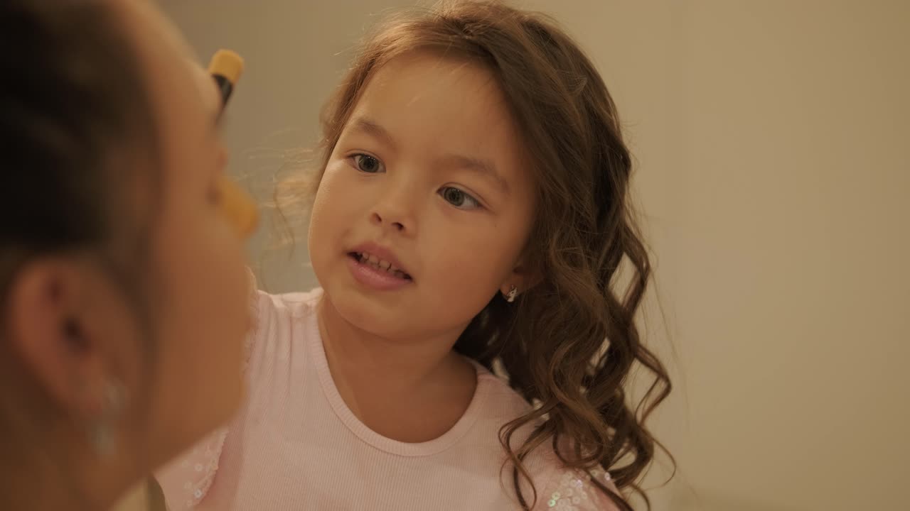 niña pequeña aplicando maquillaje a su madre embarazada en casa