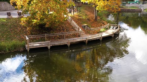 wooden pier on calm lake water in autumn season, aerial orbit view