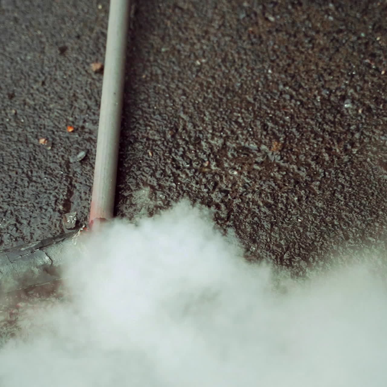 A hot water flow on the asphalt from a burst pipe creating steam in a cold weather. Breakthrough tubes. Emergency situation. Close-up.