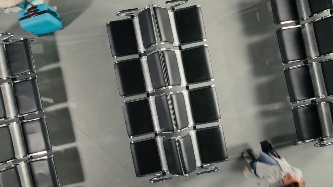 Top down view of crowd walking with trolleys and backpacks in busy airport