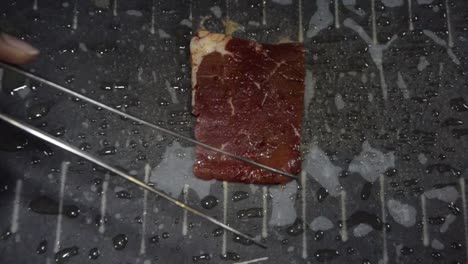 rebanada delgada de carne de res colocada y cocinada en barbacoa de piedra caliente, cámara lenta cerrada