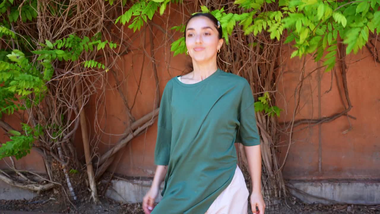 A woman near a wall with foliage