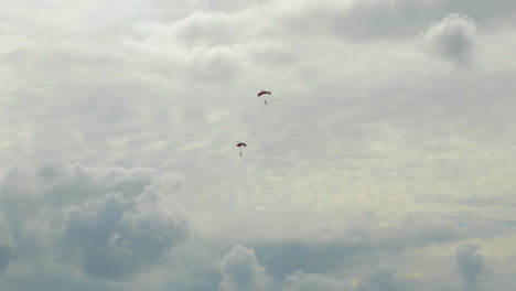 two single skydivers with open parachutes slowely glide down to earth