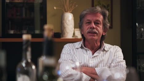 un anciano con mangas largas a rayas conversando mientras estaba en la mesa del comedor durante el almuerzo