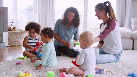 Schwarze-Und-Weiße-Frauen-Sitzen-Auf-Dem-Boden-Und-Spielen-Mit-Kleinkindern