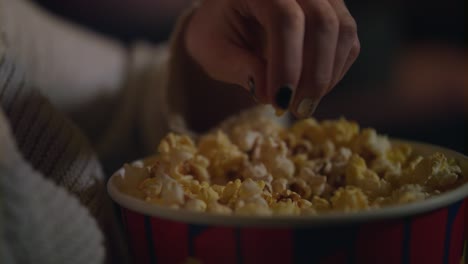 Weibliche-Hand-Pflückt-Popcorn-Aus-Papiereimer,-Nahaufnahme.-Popcorn-Im-Kino-Essen