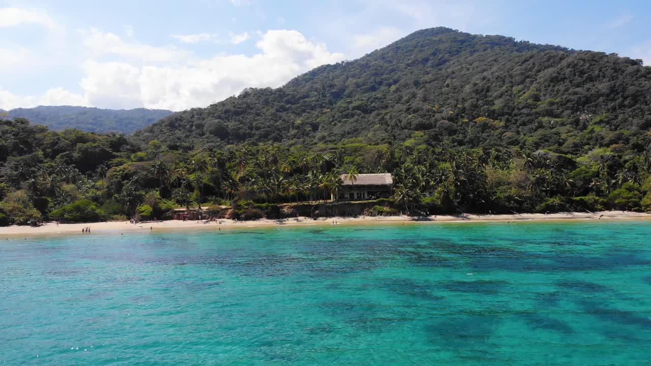 vista aérea sobre el mar poco profundo y turquesa, con vistas a una playa y la selva en la costa del parque natural nacional de tayrona, día soleado, en colombia - seguimiento, toma de avión no tripulado