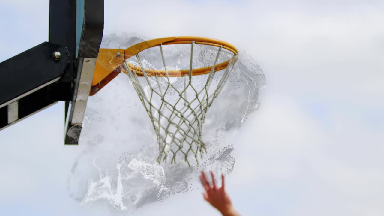 Raised arm lifting toward outdoor hoop sparking fluid swirling as ball entering net showing energy