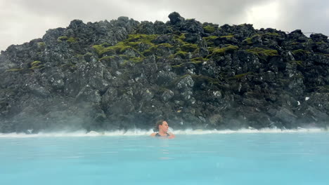 caucasian woman relaxing in blue lagoon outdoor thermal spa in iceland