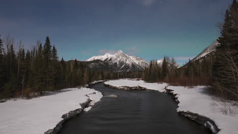 evening timelapse of a melting river in the canadian rockies with northern lights appearing