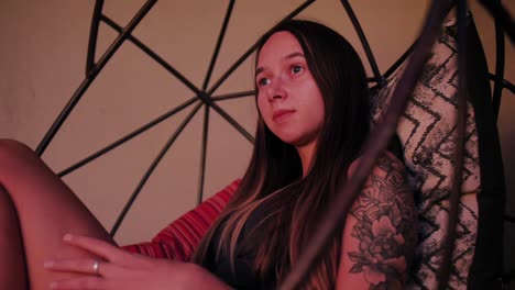 a woman sitting in a hanging chair looking into the distance