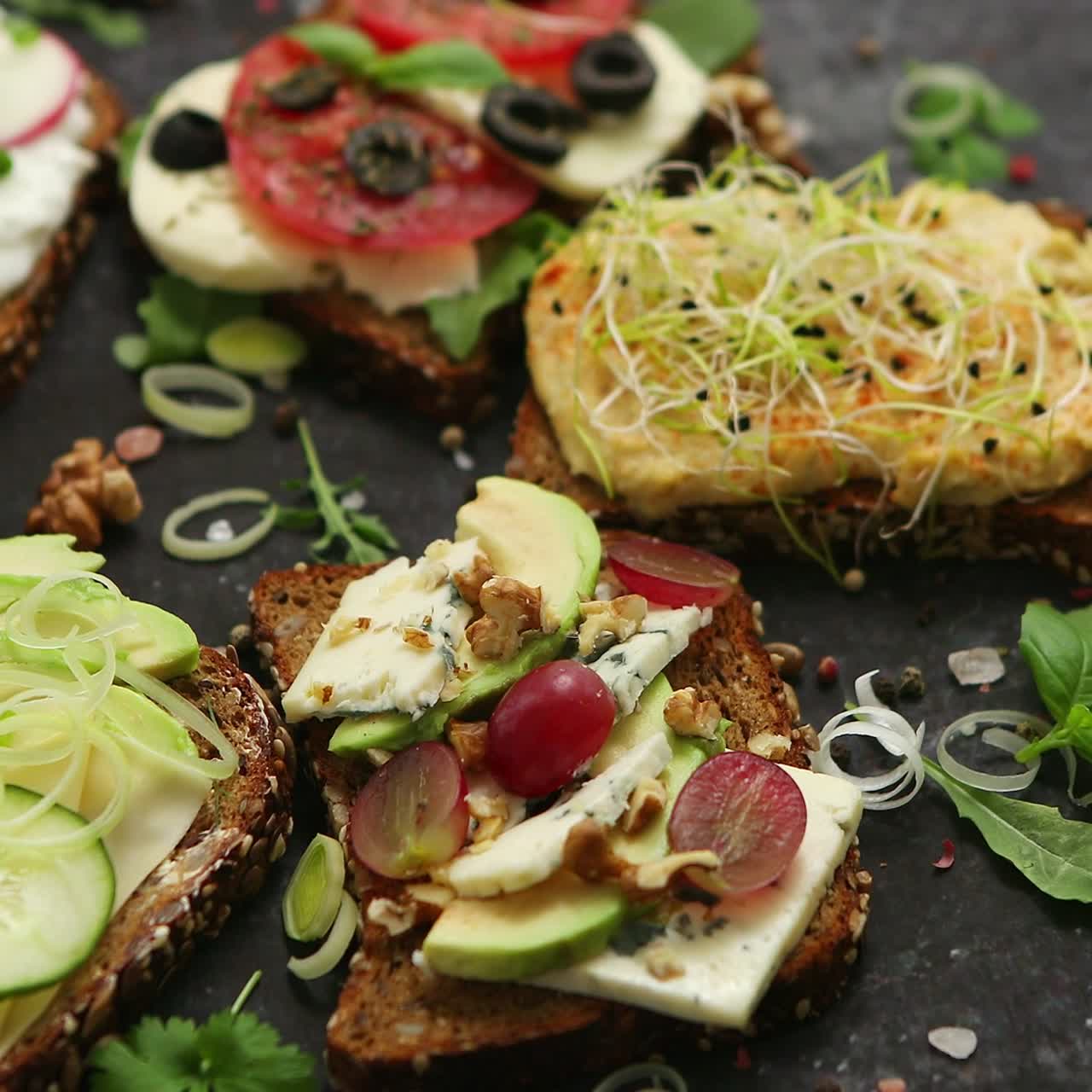 Udvalg af sunde friske sandwich med forskellige grøntsager, krydderurter og ingredienser på mørkt bord