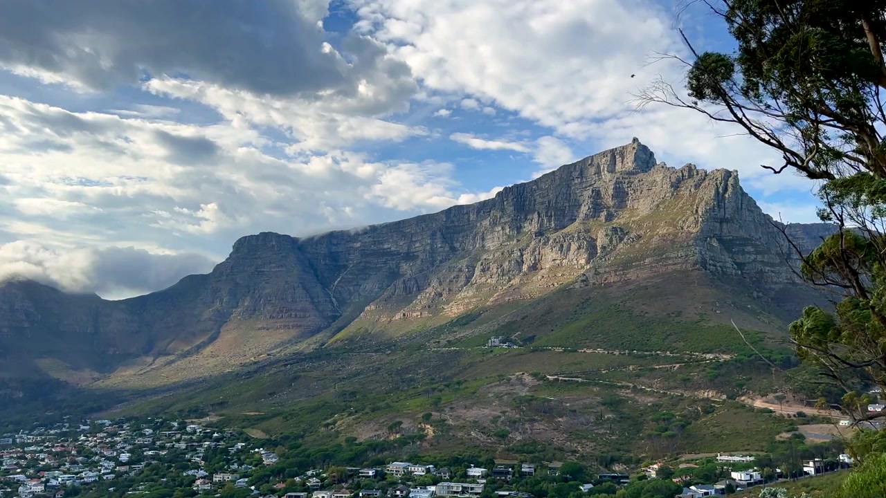 Table Mountain che si erge in modo prominente sopra i sobborghi di Città del Capo. Sudafrica. Ideale per promozioni di viaggio o documentari geografici.