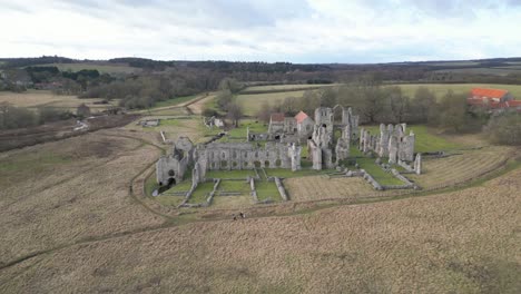 Ruinas-Del-Priorato-De-Castle-Acre-En-Norfolk,-Con-Campos-Circundantes-Y-Un-Cielo-Despejado,-Vista-Aérea