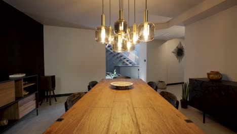 slow establishing shot of a wooden dining table with a modern kitchen
