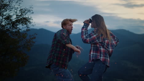 excited travelers dance sunset outdoors on holiday closeup. couple jump campfire