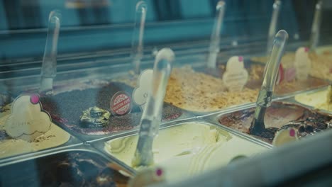 selection of gelato flavors in a glass display with scoops and labels
