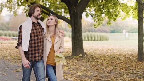 una pareja alegre caminando en el parque de otoño