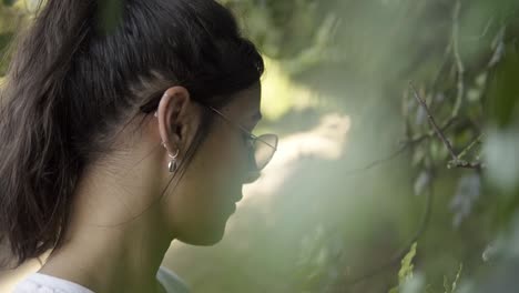 rotating shot of a model looking at the new life growing on the low-hanging branches