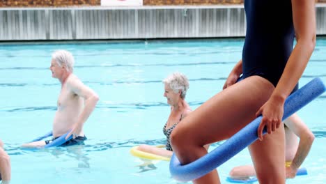 entrenador de natación ayudando a las personas mayores a realizar ejercicios