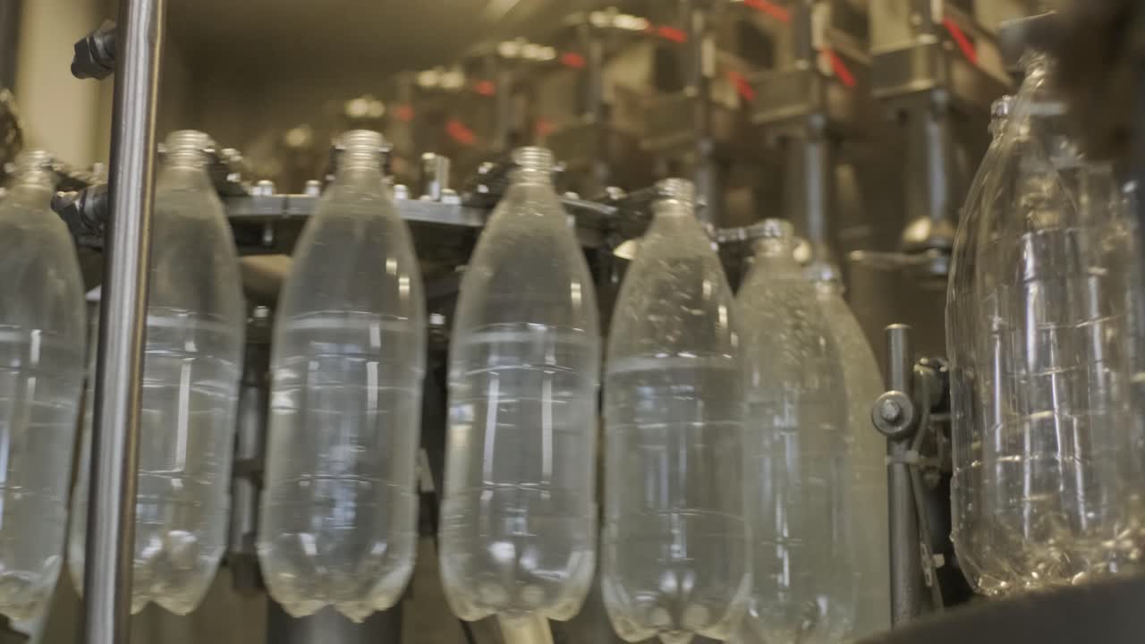 la máquina de llenado automático vierte agua en botellas de plástico para mascotas en una moderna planta de bebidas