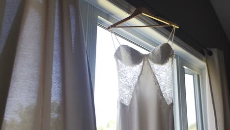 beautiful white wedding dress hanging on a window in an old wooden home