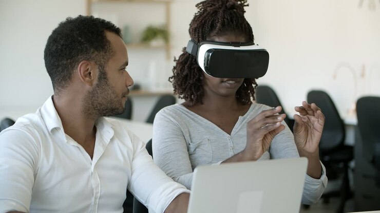 Utilisateurs enthousiastes testant un casque de réalité virtuelle, assis au bureau
