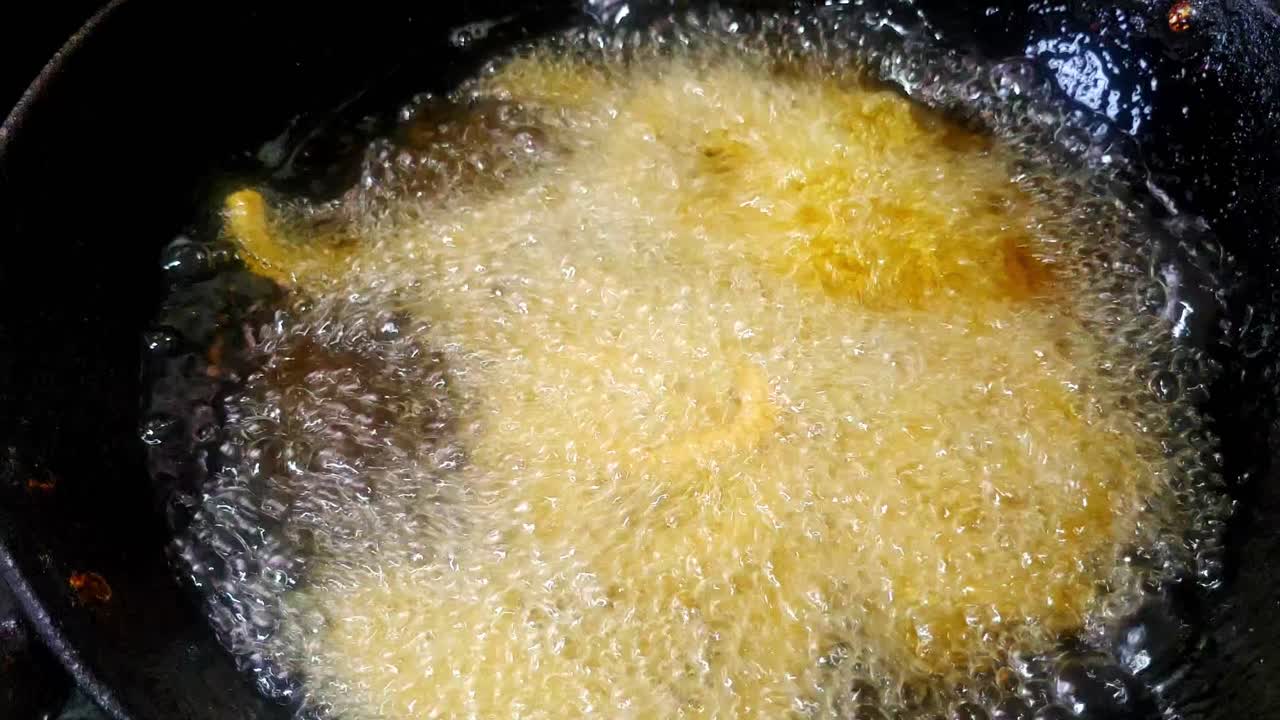 Person dropping the murukku or twisted snack in hot oil to fry. internal shot, static shot, 4k