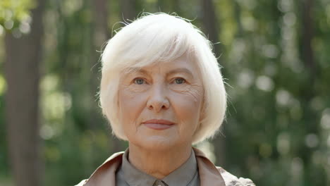 Portrait-Of-Senior-Grey-Haired-Lady-Standing-In-Wood