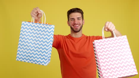 happy man holding shopping bags on yellow background