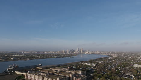 aerial flyover of a neighborhood outside of new orleans revealing the mississippi river and downtown in the background