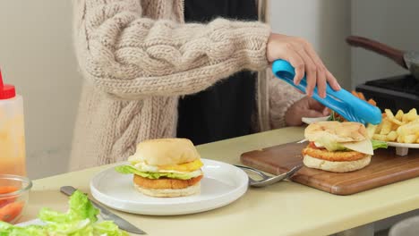 Frau-Legt-Hausgemachten-Cheeseburger-Mit-Pommes-Frites-Auf-Den-Teller