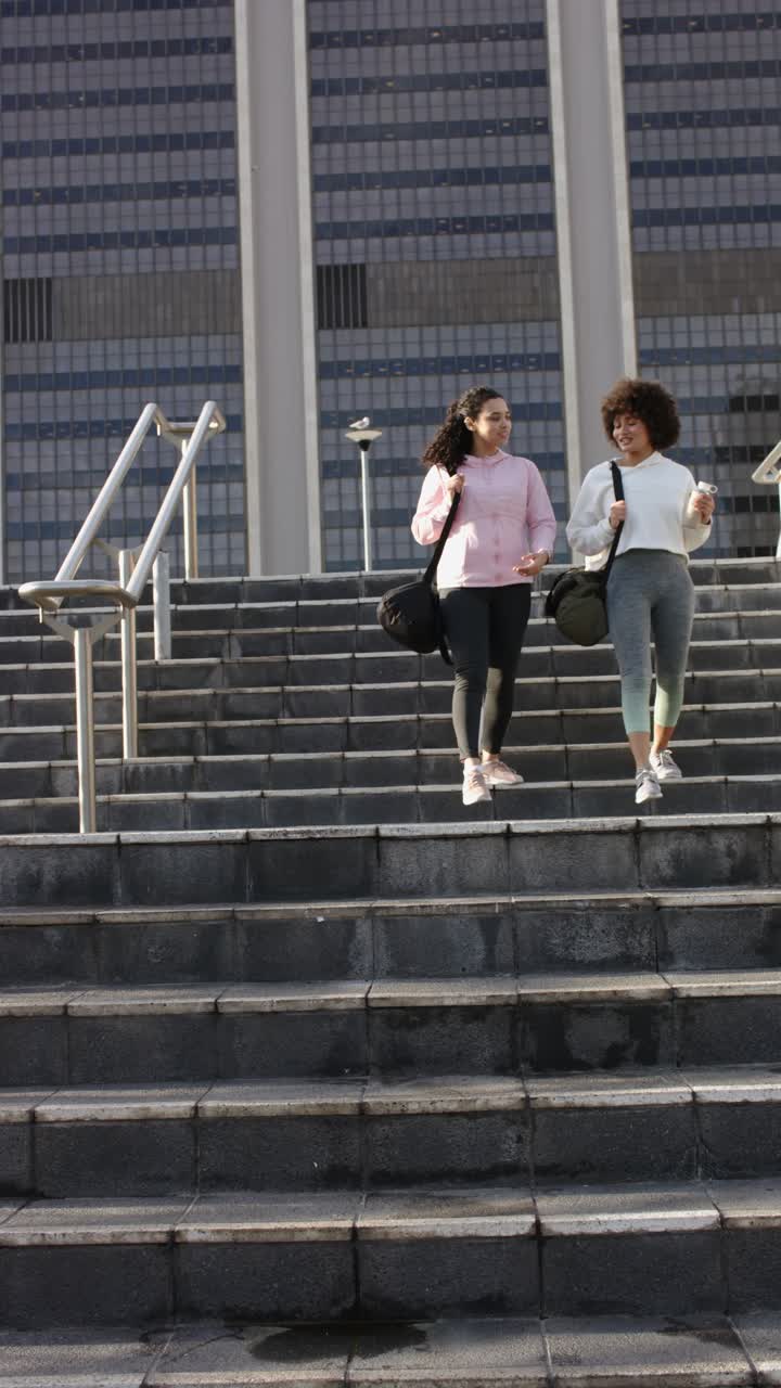 Video verticale: diverse amiche che scendono le scale con borsoni al seguito, sorseggiando un caffè e chiacchierando