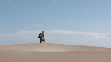 backpacker in the desert walking over a dune