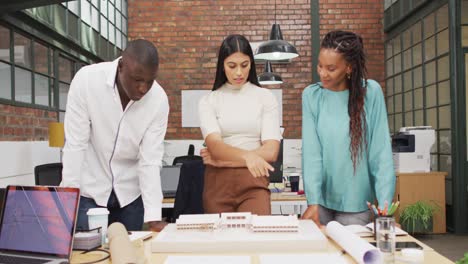 happy diverse architects looking at architectural models at office