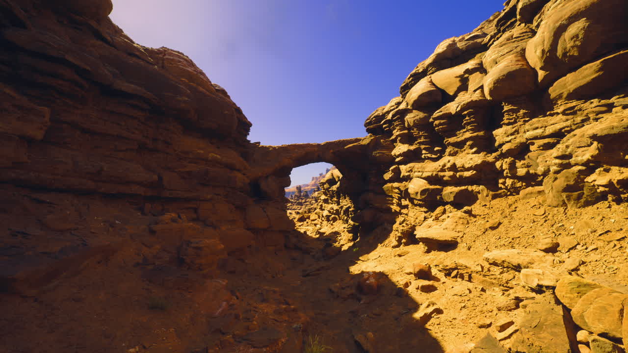 Natural rock archway in a rugged desert landscape under clear blue sky