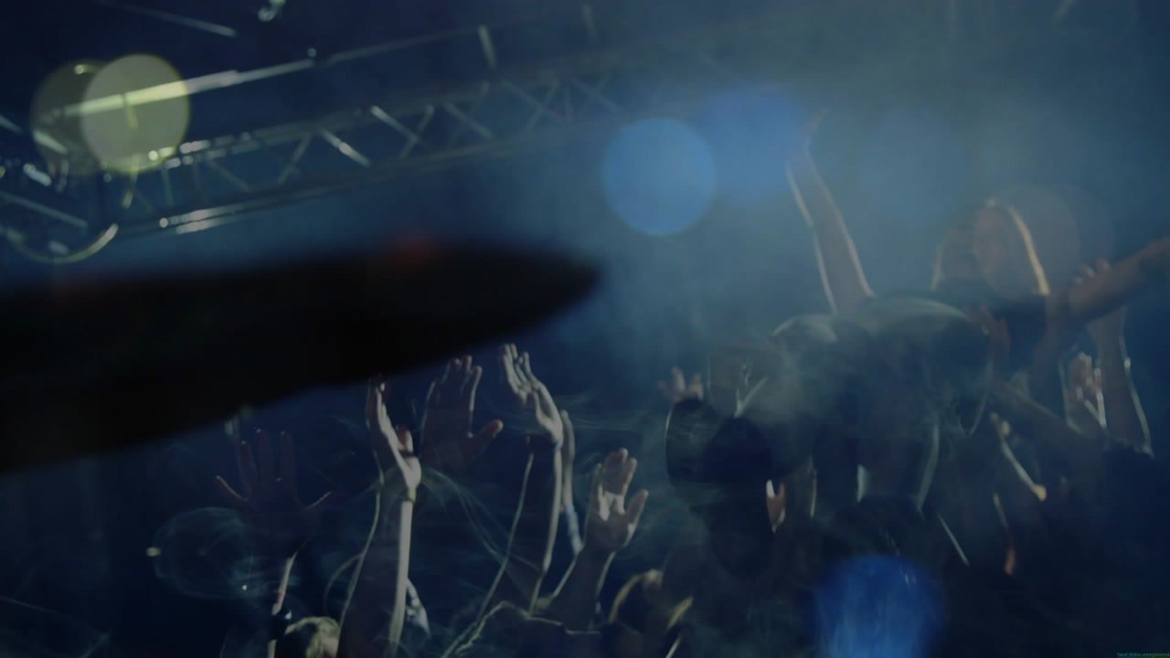Audience starting surge, lifting crowd-surfing person celebrating concert, lights and orange blur