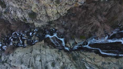 Antenne-Eines-Flusses-Ein-Wasserfall-Mit-Wasser,-Das-Von-Den-Bergen-Herunterkommt