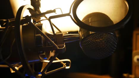 Slow-pan-left-back-lit-close-up-of-studio-microphone