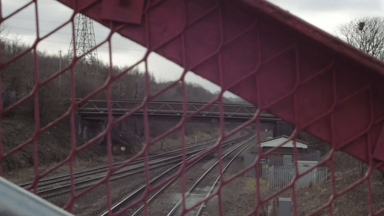 Empty train tracks pov through fencing landscape