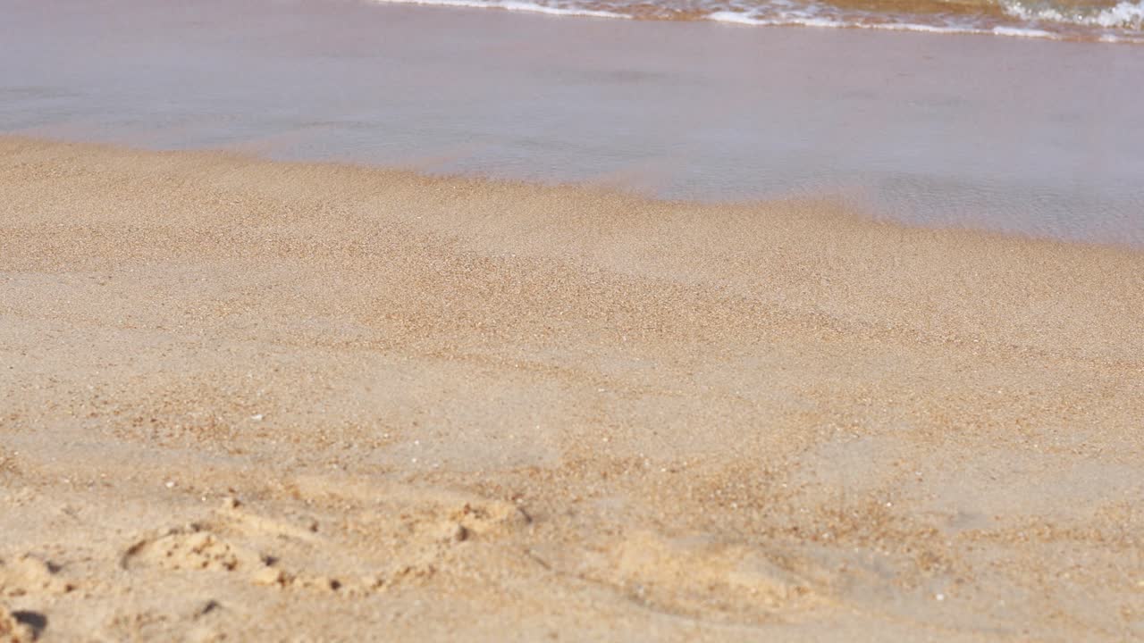 Calm waves gently wash over a sandy beach in Phuket, Thailand, under soft natural lighting, creating a serene and tranquil atmosphere