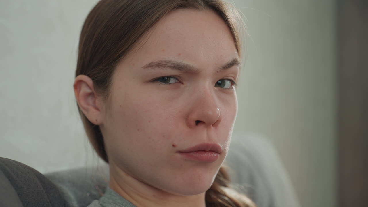 Pregnant caucasian woman closeup portrait expressing mixed emotions, introspective expectant mother with braided hair, subtle tears and thoughtful gaze, soft light, intimate domestic moment