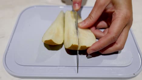 hand slicing a pear on a cutting board