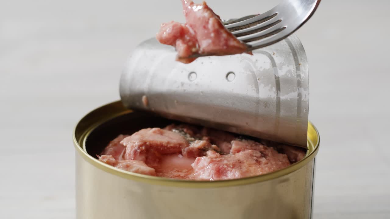 Smoked cod liver in oil in open tin can with fresh greens on wooden table. Seafoods delicacy. High quality 4k footage