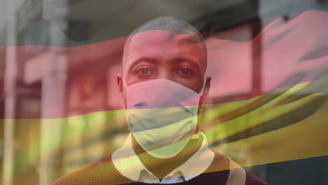 animation of flag of germany waving over african american man wearing face mask in city street