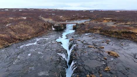 Bruarfoss-Wasserfall-In-Island-Mit-Leuchtend-Blauem-Wasser-Und-Felsiger-Landschaft,-Luftaufnahme